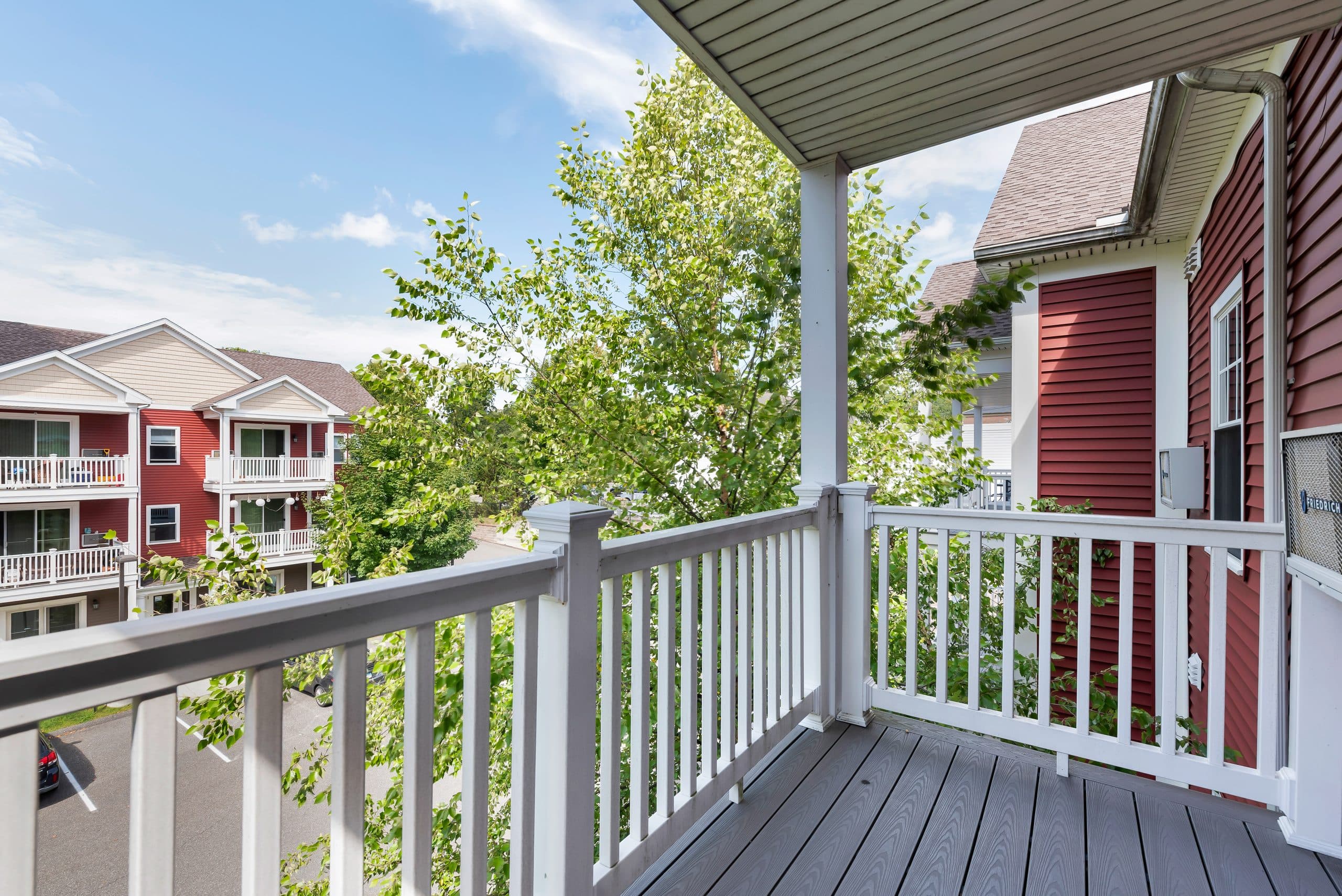 The view from a private balcony at Barton Commons, looking out through white railings over the courtyard trees